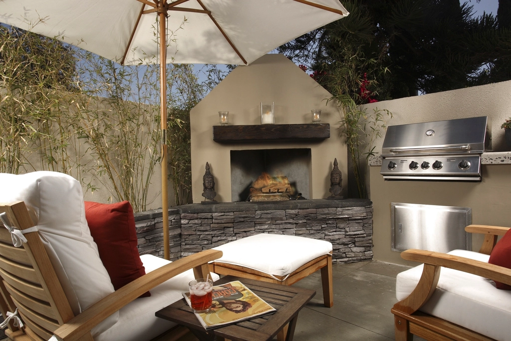 Covered outdoor kitchen with a stone fireplace and lounge seating